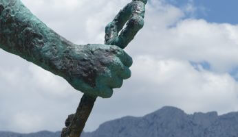 Hand einer Statue mit Wolken im Hintergrund