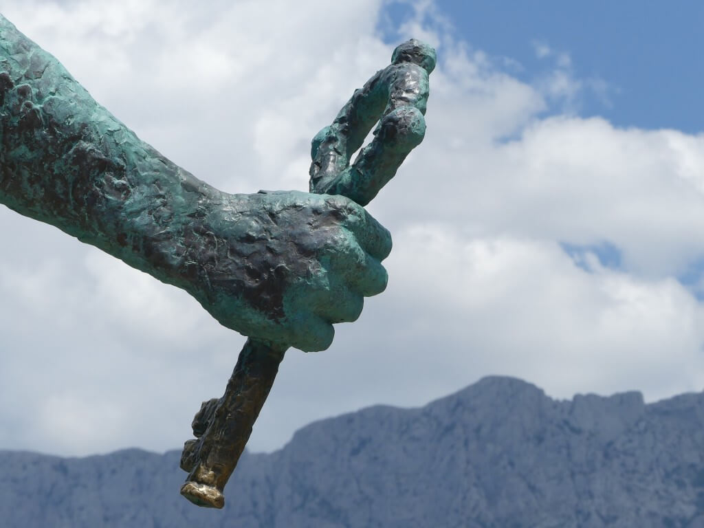Hand einer Statue mit Wolken im Hintergrund