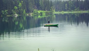 Ein Angler im Boot auf einem See mit Regentimmung.
