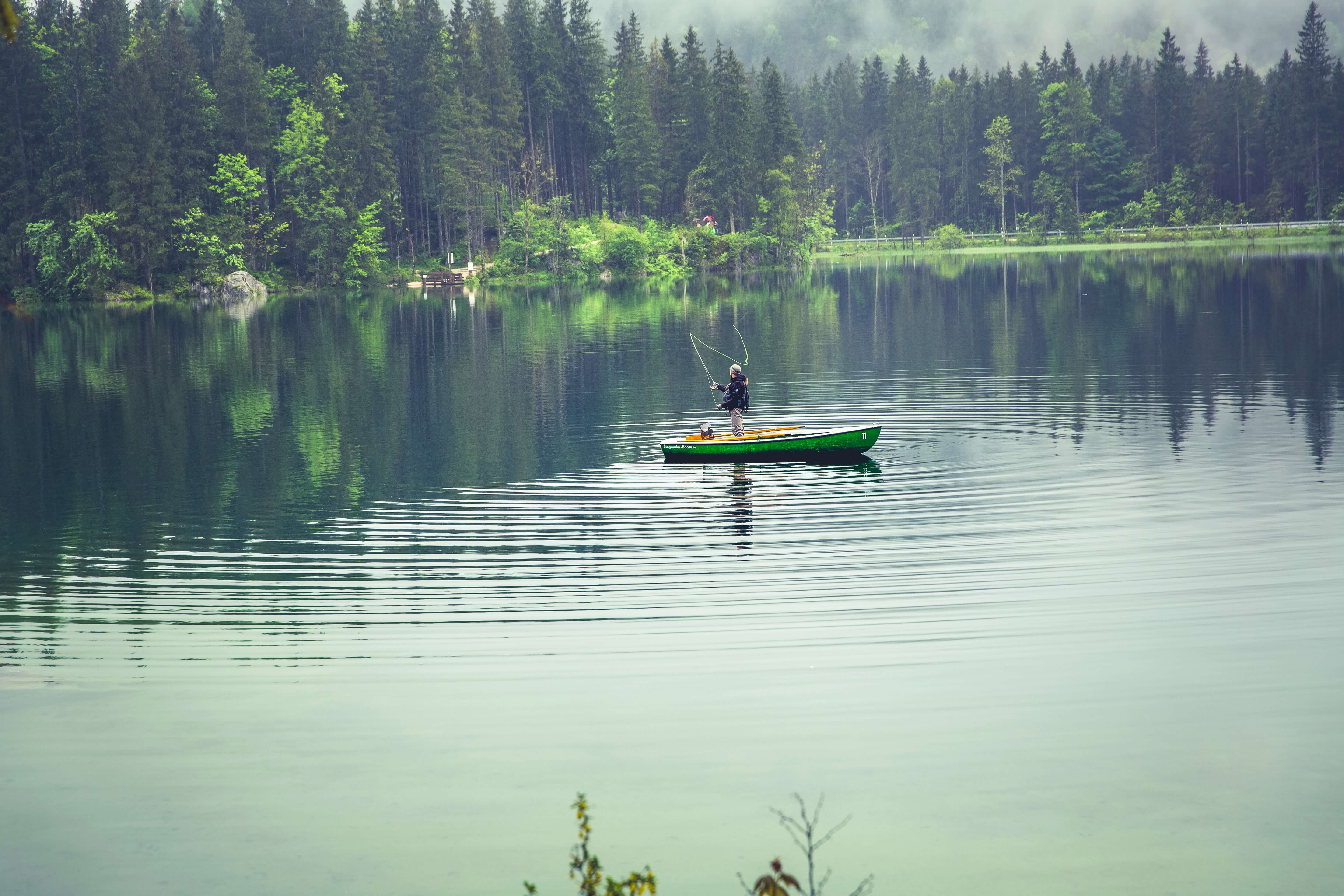 Ein Angler im Boot auf einem See mit Regentimmung.