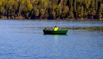 Ein Boot auf einem See mit Angler mit herbstlichen Bäumen im Hintergrund.