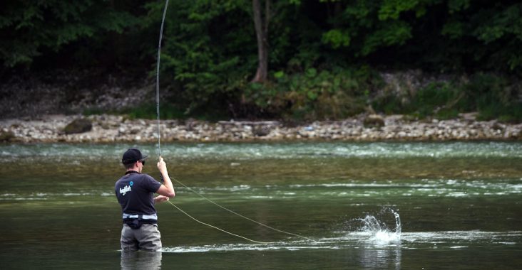 Ein Fliegenfischer mit hejfish Shirt in einem Bach gerade am Fisch fangen.