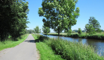 hadelner kanal mit Radweg und Bäumen an einem Schönwetter Tag.